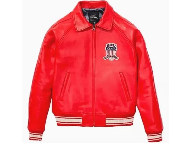 May include: A vibrant red leather jacket with a classic bomber style. Features a collared neckline, a front zipper, and two front pockets. The cuffs and hem have a white and red striped design. An embroidered patch is on the left chest.