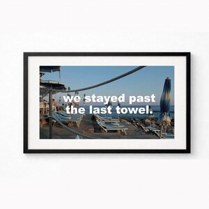 Könnte beinhalten: Gerahmter Druck mit einer Strandszene mit Liegestühlen, Sonnenschirmen und dem Meer unter blauem Himmel. Der Text "we stayed past the last towel" ist auf das Bild gelegt und erzeugt eine ruhige und eindrucksvolle Ästhetik.