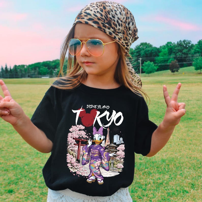 May include: Black t-shirt with a graphic of Daisy Duck in a kimono, cherry blossoms, and the text "Disneyland Tokyo." The shirt is worn by a person wearing a leopard print scarf and sunglasses.