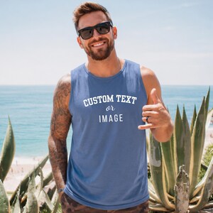 May include: A blue sleeveless tank top featuring the white printed text CUSTOM TEXT or IMAGE centered on the chest. The garment has a crew neckline and a standard fit, designed for casual wear with a clear, legible font style.