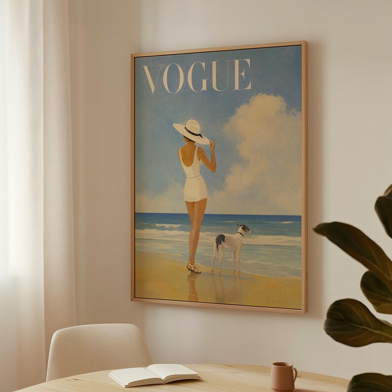 May include: Framed vintage Vogue magazine cover art. The artwork depicts a woman in a white swimsuit and hat standing on a beach with a dog. The background features a blue sky, clouds, and ocean. The word "VOGUE" is at the top.