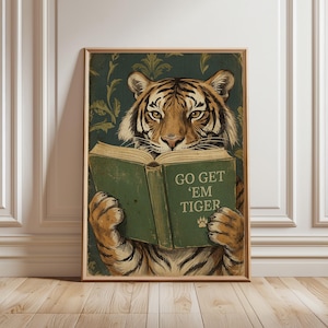 May include: A framed print featuring a tiger reading a book with the text "GO GET 'EM TIGER". The tiger is depicted with orange and black stripes, set against a green floral background. The book is green with a paw print.