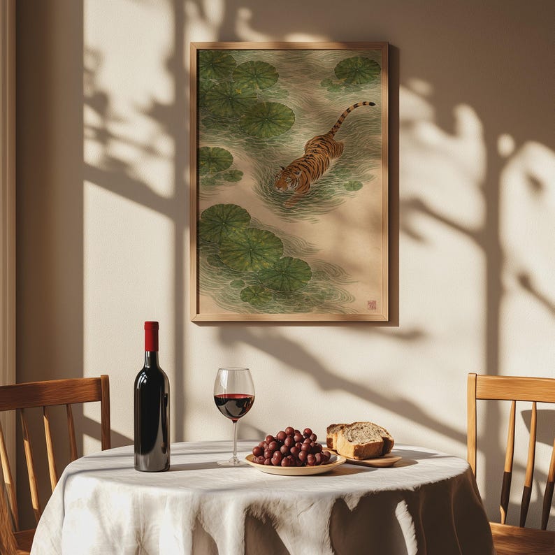 Puede incluir: Una impresi&oacute;n enmarcada de un tigre en un estanque con nen&uacute;fares. Una botella de vino tinto, una copa de vino tinto, uvas y pan est&aacute;n sobre una mesa redonda con un mantel blanco. La impresi&oacute;n est&aacute; en un marco de madera.