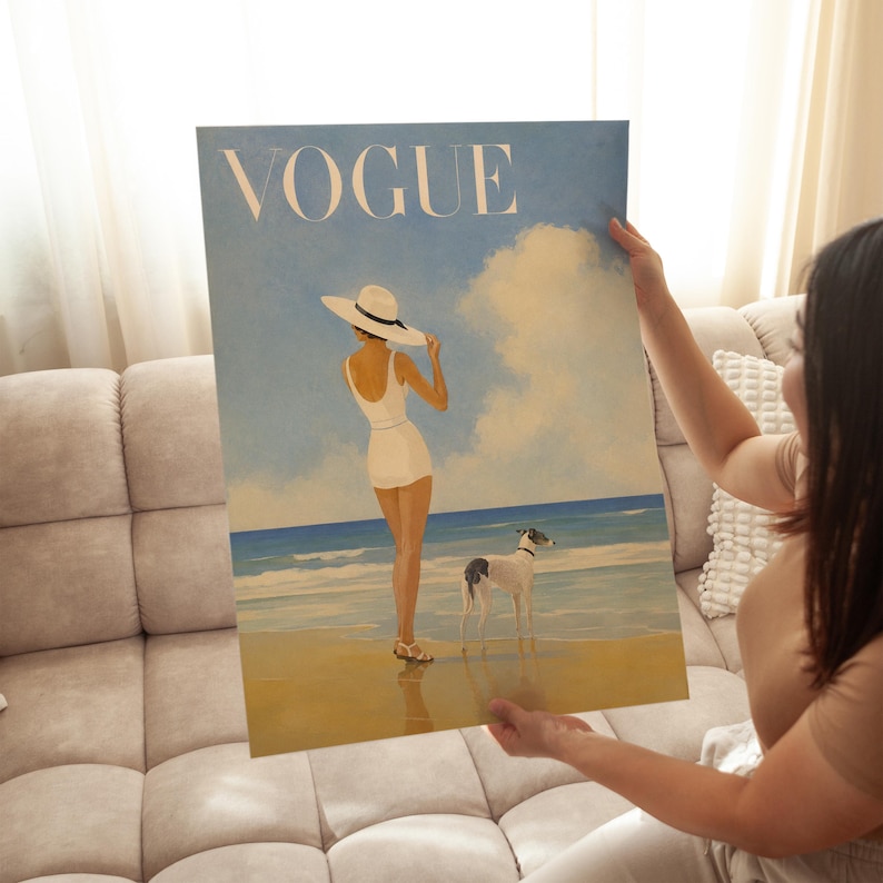 May include: A canvas print of a vintage Vogue magazine cover. The artwork depicts a woman in a white swimsuit and hat on a beach with a dog. The word "VOGUE" is printed in large, light-colored letters at the top.