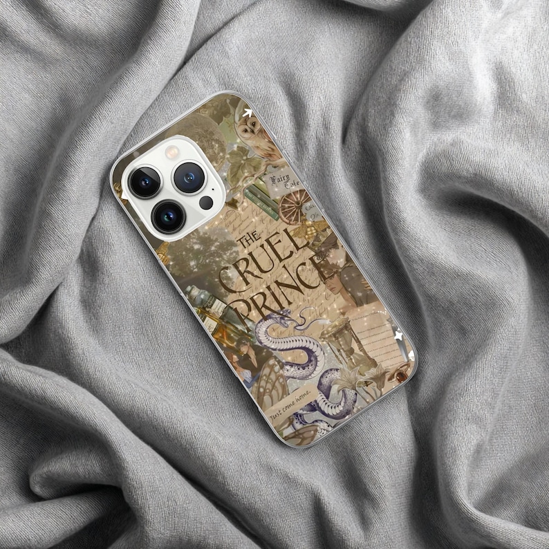 May include: A clear phone case featuring a collage design with the text "The Cruel Prince." The design includes an illustration of a snake, an owl, and other fantasy elements. The case is on a gray fabric surface.