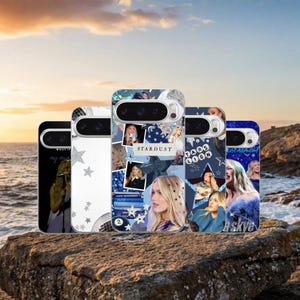 Könnte beinhalten: Eine Sammlung von Handyhüllen mit verschiedenen Designs. Eine Hülle zeigt eine Collage mit dem Wort "Stardust", andere zeigen Bilder und Text. Die Hüllen sind in verschiedenen Farben, darunter Weiß, Blau und Schwarz, und liegen auf einem Felsen am Meer.