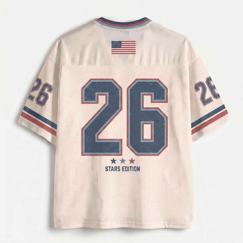 May include: A cream-coloured mesh jersey featuring the number 26 in large navy blue font with a red outline on the back. The shirt includes a small American flag graphic at the neckline, the text STARS EDITION with three stars, and the number 26 on sleeves.