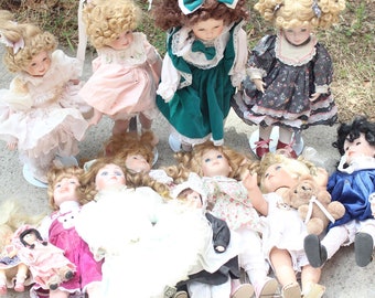 Puede incluir: Una colección de muñecas de porcelana vintage, cada una con detalles y vestida con varios atuendos. Las muñecas tienen cabello rubio rizado u oscuro, y algunas visten vestidos en tonos rosa, verde y azul. Algunas muñecas están de pie, otras están tumbadas.