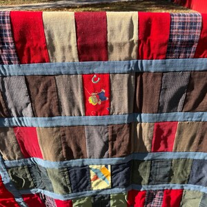 May include: A patchwork quilt with a variety of fabrics in red, blue, brown, and beige. The quilt features a red border and blue denim-like strips. Some patches have embroidered details, including a horseshoe.