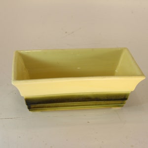 以下が含まれることがあります： 明るい黄色の上面と濃い緑色のベースを持つ長方形のプランター。 プランターは段付きのデザインで、おそらくセラミック製です。 空で、植える準備ができています。 長さは約20cmです。