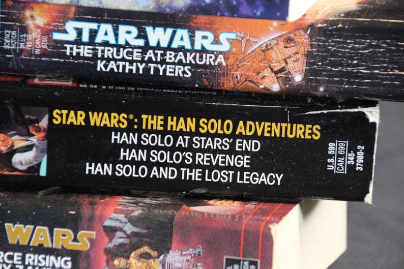 May include: Close-up of three Star Wars books. The top book is "The Truce at Bakura" by Kathy Tyers. The middle book is "Star Wars: The Han Solo Adventures" with titles "Han Solo at Stars' End", "Han Solo's Revenge", and "Han Solo and the Lost Legacy".