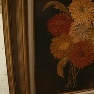 May include: Oil painting of a bouquet of flowers in shades of orange, yellow, and gold against a black background. The painting is in a gold-colored frame.