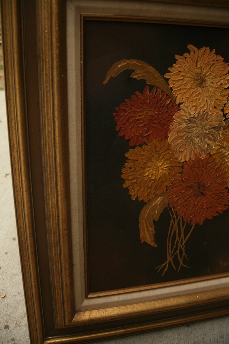 May include: Oil painting of a bouquet of flowers in shades of orange, yellow, and gold against a black background. The painting is in a gold-colored frame.