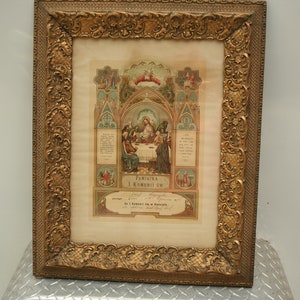 May include: Ornate gold-colored framed religious print. The print features a central image of a religious scene with figures around a table. The frame has detailed scrollwork. Text in Polish is visible.