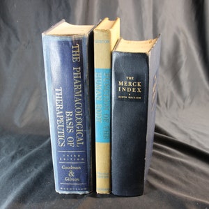 Puede incluir: Se muestran tres libros de texto médicos antiguos, cada uno con un color y título diferentes. Los libros incluyen "The Pharmacological Basis of Therapeutics", "Function of the Human Body" y "The Merck Index". Los libros están en buen estado.