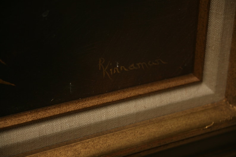 May include: A framed painting with a dark background and a gold-colored wooden frame. The artist's signature, "R. Kinaman", is visible in the upper right corner. The artwork is mounted on a canvas.