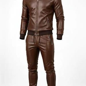 May include: A brown leather tracksuit, featuring a zip-up jacket with a stand-up collar and matching pants. The jacket has a front zipper and side pockets. The pants have a drawstring waist and zippered pockets. The cuffs and waistband are ribbed.