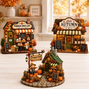 May include: Three miniature autumn-themed buildings including a Pumpkin Spice Cafe, a Hello Autumn coffee shop, and a Pumpkin Patch scene. Each structure features detailed fall foliage, pumpkins, signage with text, and warm interior lighting.