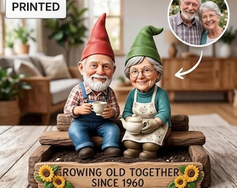 May include: A 2D flat printed garden ornament featuring two gnomes sitting on a wooden bench. The male gnome wears a red hat and blue overalls, while the female gnome wears a green hat and floral apron. The base reads GROWING OLD TOGETHER SINCE 1960.