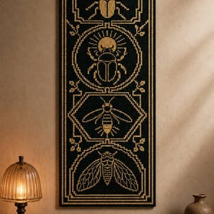 May include: A vertical rectangular cross-stitch wall hanging featuring a black fabric background with four stacked gold-stitched insect designs, including a stag beetle, a scarab, a bee, and a cicada, all enclosed within geometric borders.