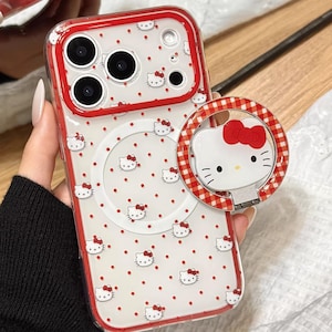 May include: A clear phone case with a red border and a white background dotted with red spots and Hello Kitty faces. A matching phone ring holder is attached. The text "Cute V Case" is at the bottom.