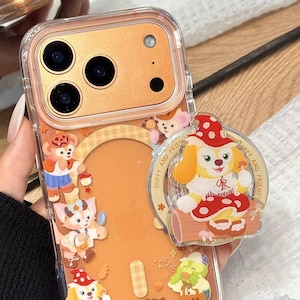 May include: Clear phone case with a gold-colored back and a variety of cartoon character designs. The case features the text "Duffy and Friends" and "Cute V Case". The case has a pop-up grip with a cartoon dog design.