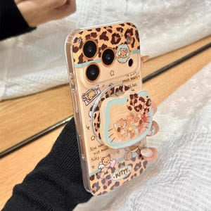 May include: A clear phone case with a leopard print design and a pop-up grip featuring a cartoon bear and other characters. The case has the word "KITTY" and the text "Also need nice music Kitty".