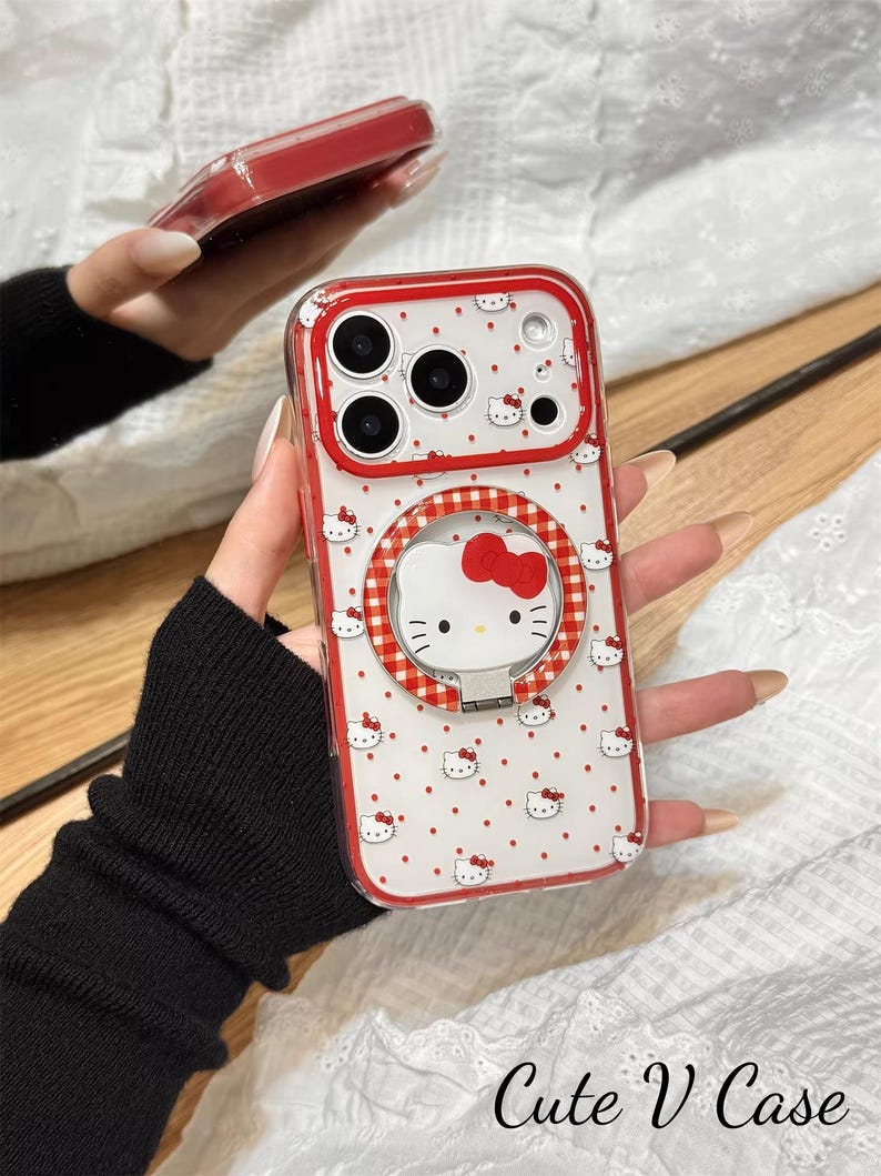 May include: Clear phone case with a red border and a white background covered in small red Hello Kitty faces. The case has a red and white gingham ring holder with a Hello Kitty face and a red bow. The text "Cute V Case" is at the bottom.