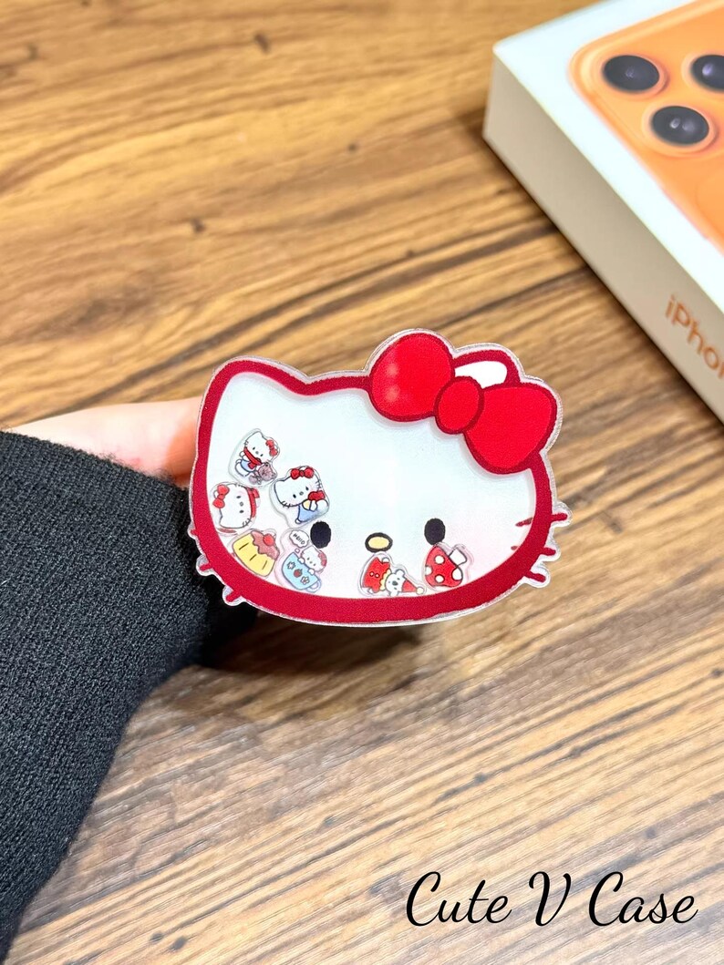 May include: A clear phone case with a red-outlined Hello Kitty design and a red bow. The case has a white interior with small Hello Kitty figures. The text "Cute V Case" is at the bottom.