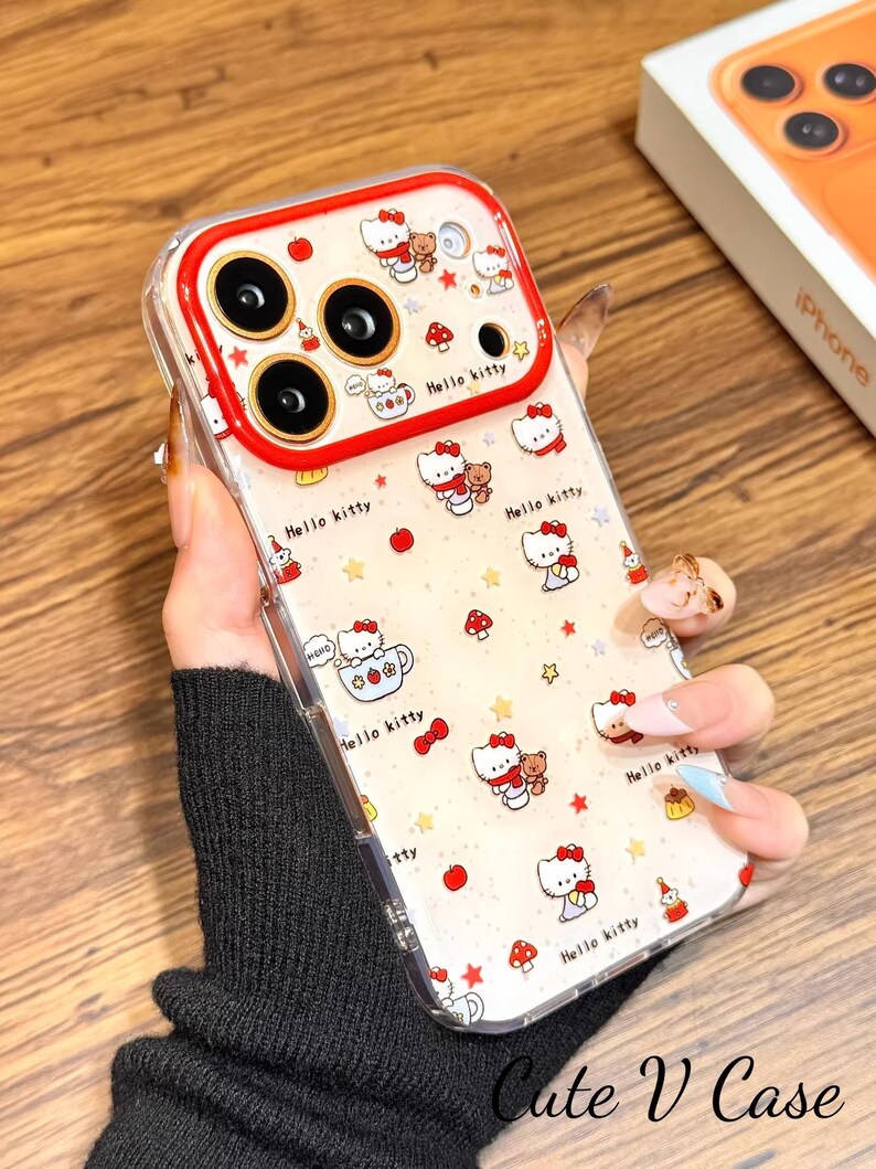 May include: Clear phone case with a Hello Kitty design and red detailing. The case features a red camera border and is decorated with Hello Kitty characters, stars, mushrooms, and the words "Hello Kitty". The text "Cute V Case" is also visible.