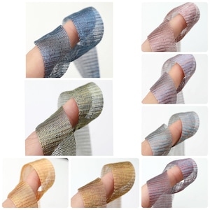 May include: A collection of metallic mesh finger sleeves in various colors, including blue, pink, gold, and silver. The sleeves are designed to fit over a finger, with a hole for the fingertip to extend through. The mesh has a woven texture.