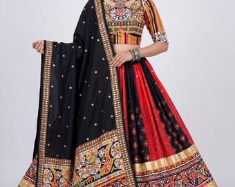 May include: A black and red lehenga choli set featuring a cropped blouse with multi-colored striped sleeves and intricate mirror work. The skirt has a wide gold border with geometric patterns, and the black dupatta is adorned with gold dots.