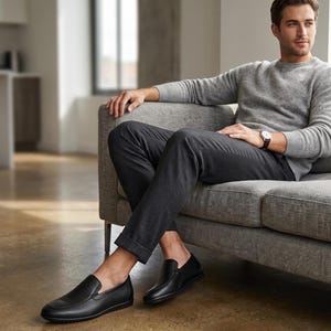 K&ouml;nnte beinhalten: Ein Paar schwarze Slipper aus Leder mit abgerundeter Spitze, glatter Oberfl&auml;che und strukturierter Gummisohle. Die Schuhe haben ein flaches Design mit elastischen Seiteneins&auml;tzen f&uuml;r einen sicheren Halt und eine schlichte Silhouette.