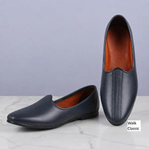 May include: A pair of dark navy blue slip-on shoes with a smooth finish, featuring a pointed toe, a central vertical stitched seam on the vamp, and a tan interior lining. The text "Walk Classic" is printed in the lower right corner of the image.