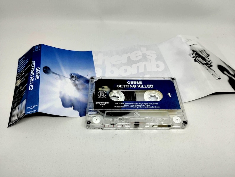 May include: A clear plastic cassette tape for the album Getting Killed by Geese, featuring a dark blue label with white text. The accompanying J-card insert displays a blue-toned image of a trumpet player and black and white text.
