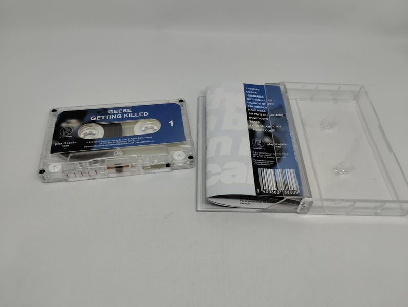 May include: A clear plastic cassette tape with a blue label reading Geese Getting Killed and a matching J-card insert featuring a tracklist including songs like Cobra and Bow Down, displayed next to an open transparent cassette case.