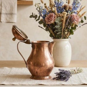 Jarra de cobre antigua martillada a mano con tapa, ideal para café o como florero.