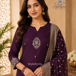 Peut inclure: Ensemble de vêtements ethniques indiens de couleur prune, comprenant une tunique à manches longues avec des détails brodés et une écharpe assortie. L'écharpe présente un motif floral doré et une bordure perlée. Le texte "Stylebyvin" est inclus.