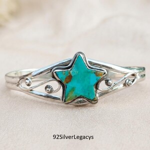 May include: A silver cuff bracelet featuring a central star-shaped turquoise inlay with brown matrix patterns. The metal band displays intricate swirling wire details on both sides of the star. The text 92SilverLegacys is visible below.