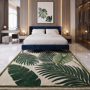 May include: A modern bedroom featuring a navy blue bed, a large area rug with a green leaf design, and a framed botanical print. The room has a neutral color palette with wood paneling and marble flooring, creating a serene atmosphere.