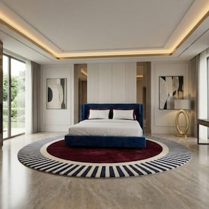 May include: A luxurious bedroom with a large blue bed, white bedding, and a round rug with a red center and striped border. The room features a walk-in closet, artwork, and a sitting area with a chair and side table.