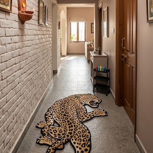 May include: A hallway rug shaped like a leopard, featuring a tan and black spotted pattern. The rug is placed on a gray tiled floor. The hallway has white brick walls and a wooden door.
