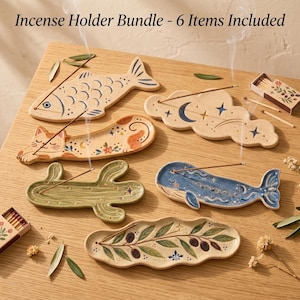 May include: Incense Holder Bundle - 6 Items Included. A collection of six ceramic incense holders featuring a fish, a cat, a cloud with moon and stars, a cactus, a whale, and an olive branch design, each holding a thin incense stick.