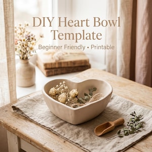 May include: A heart-shaped beige bowl filled with dried flowers and twine sits on a linen cloth. A small wooden scoop and sprig of greenery are nearby. The text "DIY Heart Bowl Template" is visible.