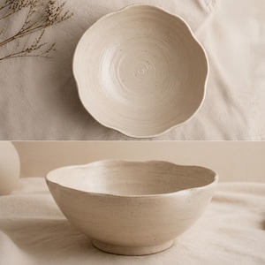 May include: A beige ceramic bowl with a wavy edge. The bowl has a round base and a textured surface. The bowl is shown from two different angles, one from above and one from the side.