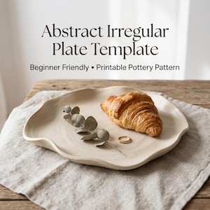 Op de afbeelding: Een beige, abstracte onregelmatige plaat met een golvende rand, met een croissant, takje eucalyptus en een gouden ring. De plaat ligt op een linnen servet. Tekst op de afbeelding luidt "Abstract Irregular Plate Template" en "Beginner Friendly • Printable Pottery Pattern."