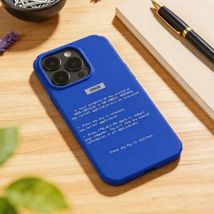 Op de afbeelding: Blauwe telefoonhoes met een schermfoutmelding. De hoes heeft een uitsparing voor een drievoudige cameralens. De tekst op de hoes luidt "ERROR" en bevat een technische foutmelding.