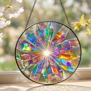 May include: A circular suncatcher featuring a radial arrangement of iridescent, multi-colored glass shards that reflect light in a spectrum of hues. The design is encased in a thin black metal frame and suspended by a black metal chain.