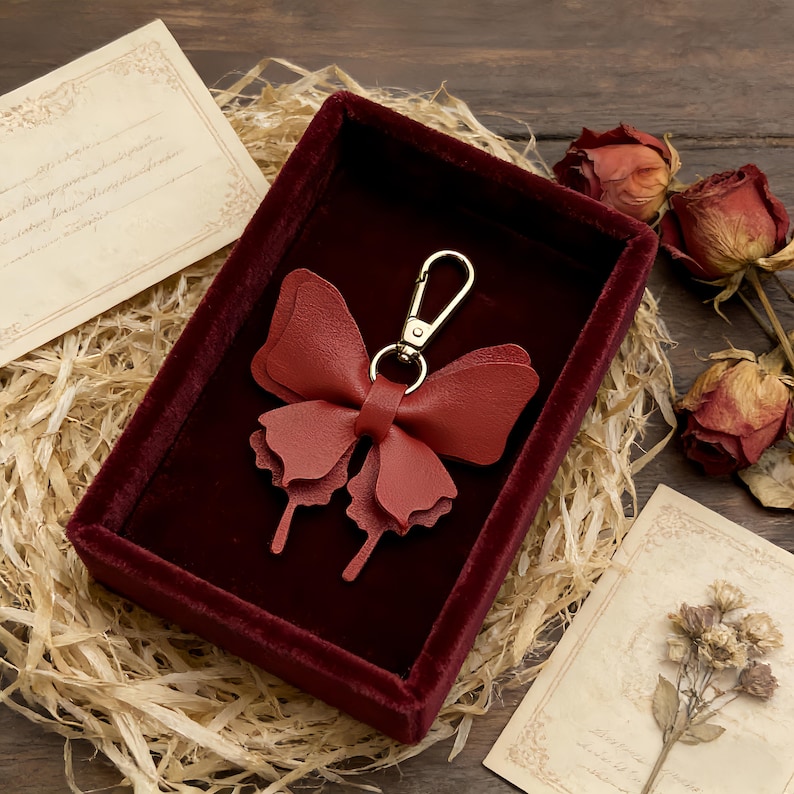 Leather butterfly keychains in multiple colors with gold clasps and cutout wing details, forest decor bag charm accessories.