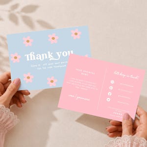 May include: A light blue thank you card featuring pink flowers with yellow centers and white text, paired with a pink business card displaying contact information, social media icons, and the phrase Let's keep in touch in white script.